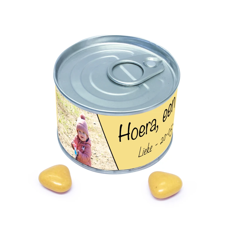 Blikje met label met gele snoepjes en Lieke hoera een zusje