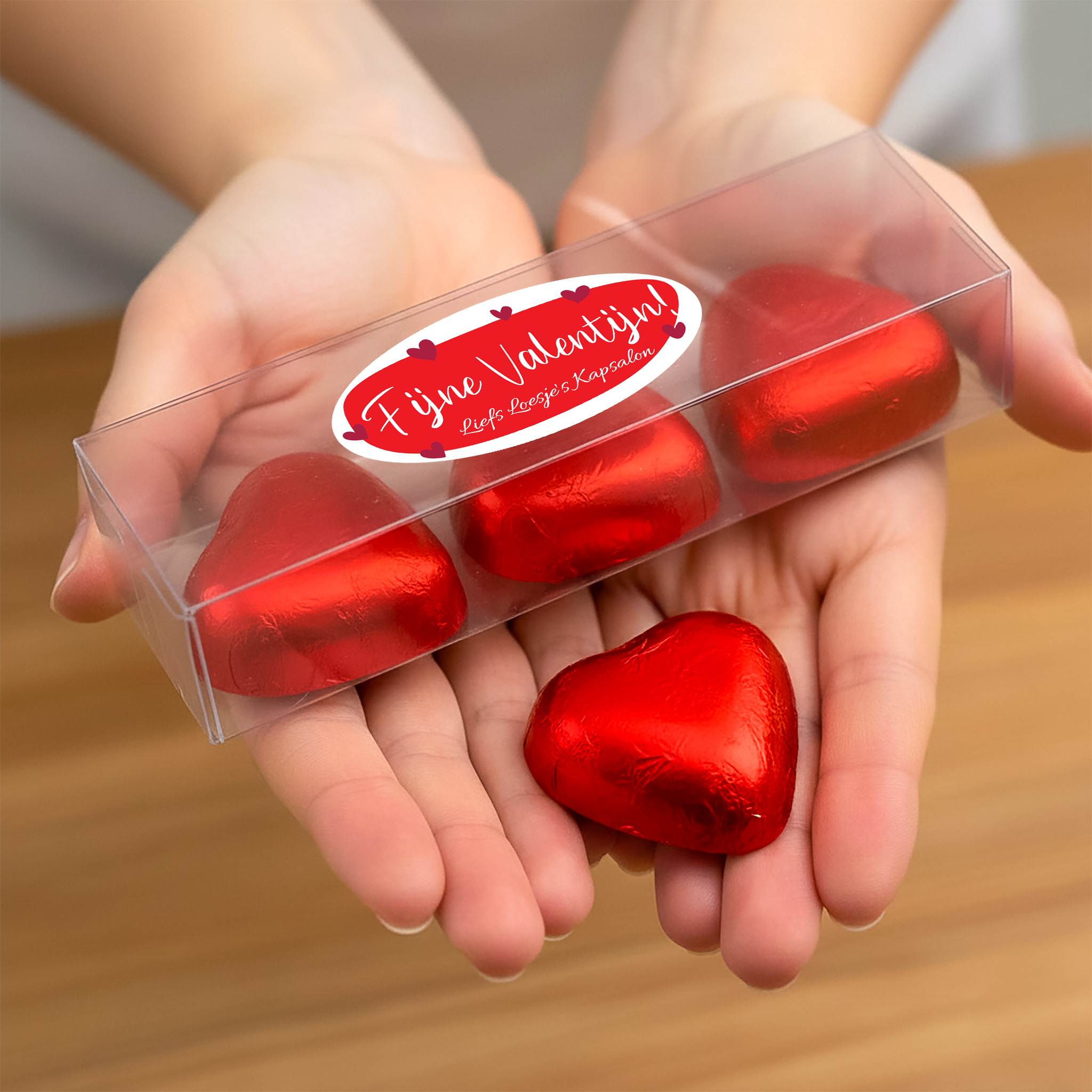 Gepersonaliseerd transparant cadeaudoosje met bonbons in handen voor Valentijnsdag